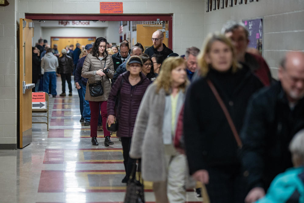 Hundreds of voters line up down a hallway of Bedford High School as the polls open in the morning in Bedford, N.H. on Jan. 23, 2024.