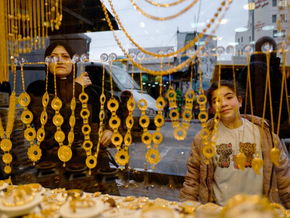 People in Ramallah look into the window of a gold store, one of the West Bank businesses affected by the economic decline resulting from Israel's war in Gaza.
