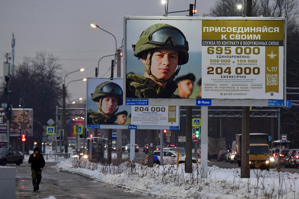A man walks past billboards promoting contract army service that read 