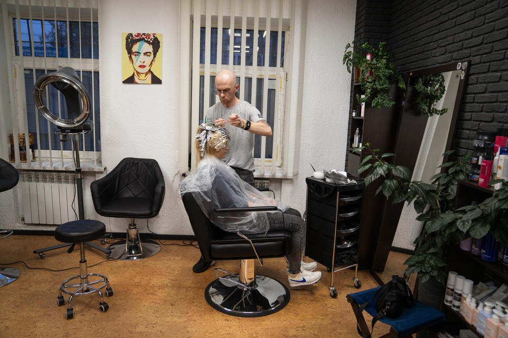 Yevhen Shcherbyna, a hairdresser in Dnipro, colors a woman's hair at his salon downtown. He hears from many clients that they're worried their family members will be conscripted.