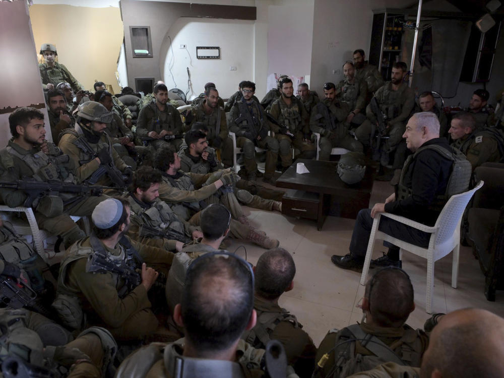 Israel's Prime Minister Benjamin Netanyahu (right) speaks to soldiers on a visit to the northern Gaza Strip on Dec. 25, 2023. Netanyahu says the militant group Hamas must be destroyed in the current war in Gaza, though some critics say that goal is unrealistic.
