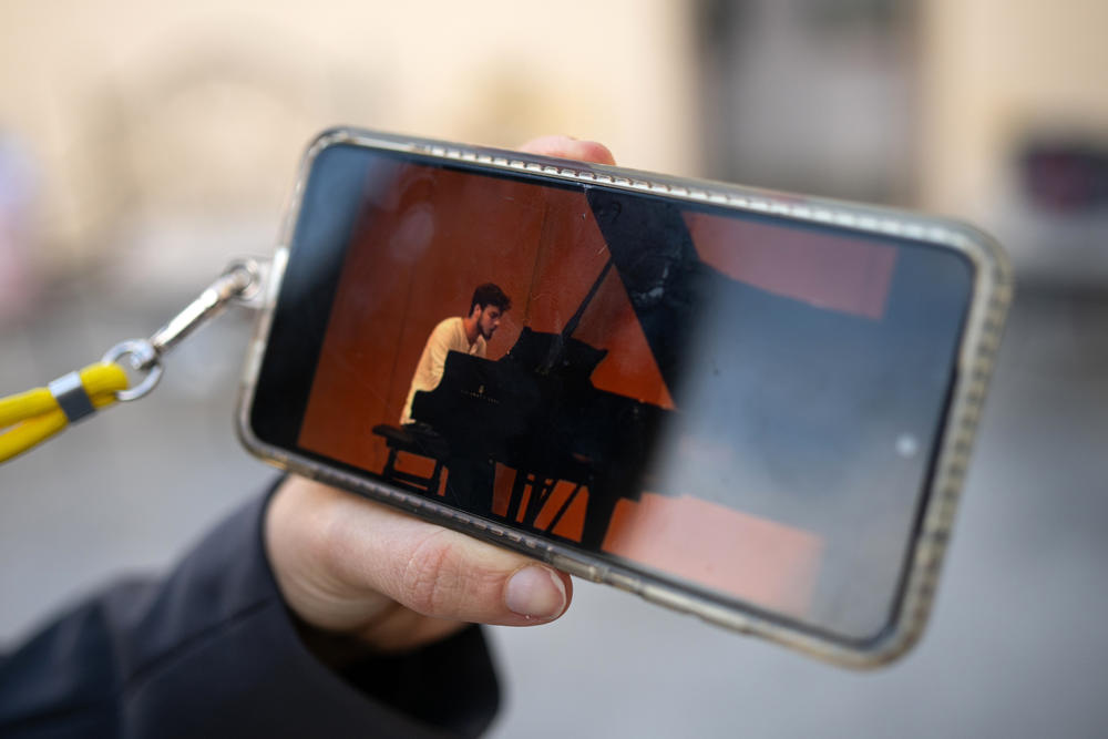 Idit Ohel holds up a video of Alon performing Claude Debussy's Clair de Lune at a youth competition.