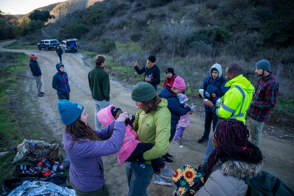 A toddler is assisted by members of humanitarian group Borderlands Relief Collective. One of the major concerns in the rugged terrain that separates Tijuana from San Diego is hypothermia.