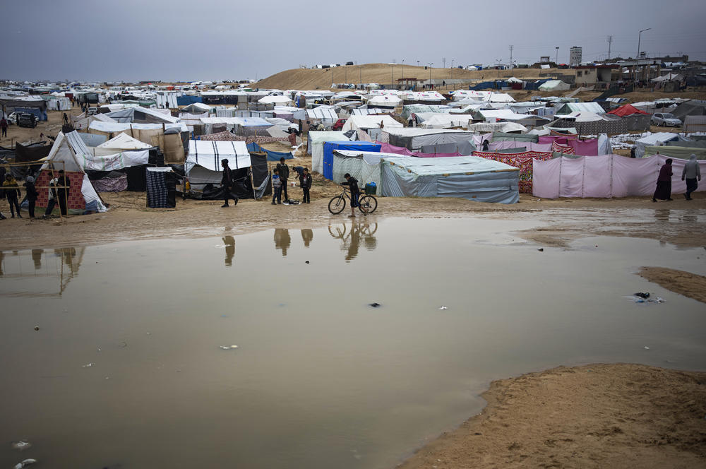 Palestinians displaced by the Israeli air and ground offensive in Gaza walk through a makeshift tent camp in Rafah on Jan. 27.