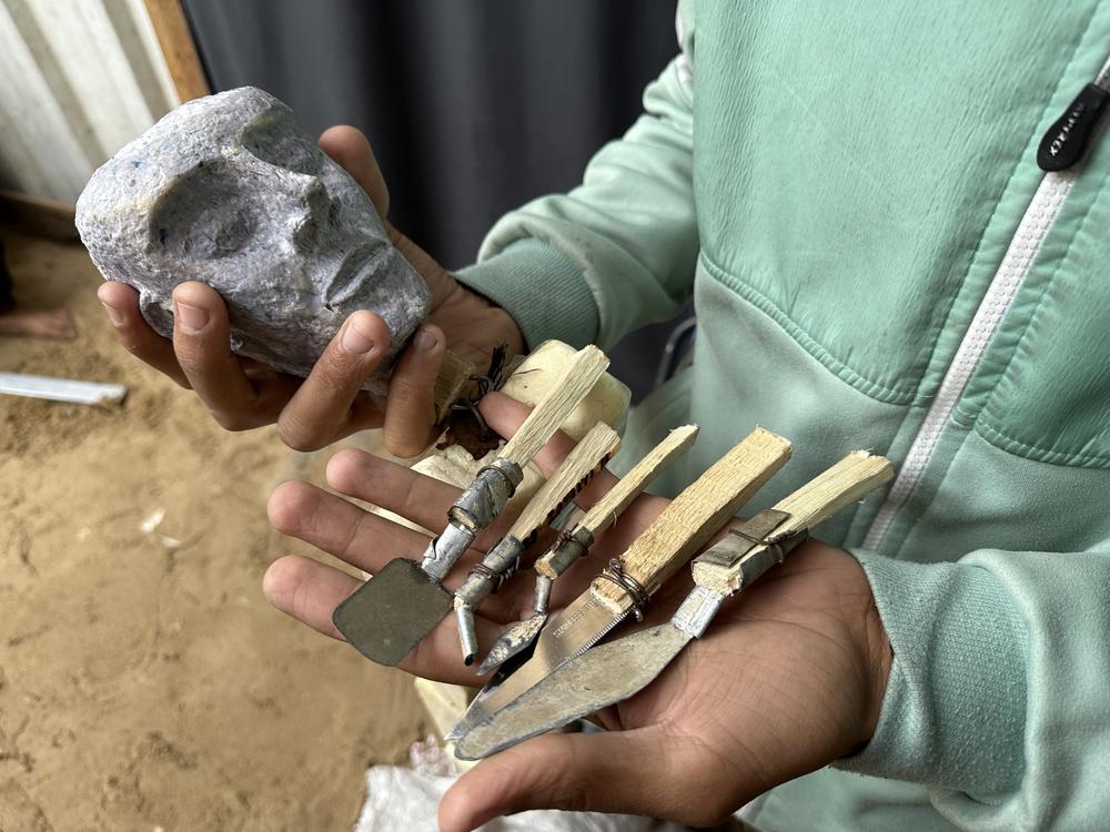 Gaza puppeteer Yousef al-Hindi shows off tools he fashioned from tin and wood and the head of the puppet he created.