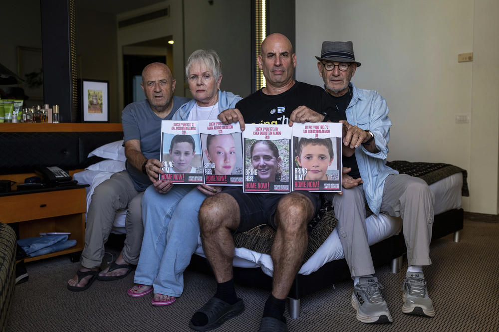 Giroa Almog (right) Varda and David Goldstein as well as Omri Almog, hold up portraits of Omri's sister, 49-year-old Chen Goldstein and her three children in a hotel in Tel Aviv, Israel, for evacuated Israelis, Monday, Oct. 30, 2023. The Israeli mother and her three children were abducted by Hamas militants from their home in the kibbutz of Kfar Aza on Oct. 7.