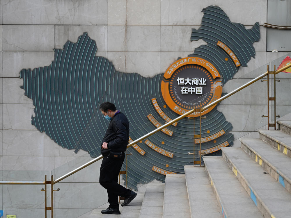 At a partially operating Evergrande commercial complex in Beijing on Monday, a man walks past a map of China that shows Evergrande's commercial complexes throughout the country. Evergrande was once listed as the world's most valuable real estate company, but on Monday, a Hong Kong court ordered it to be liquidated.