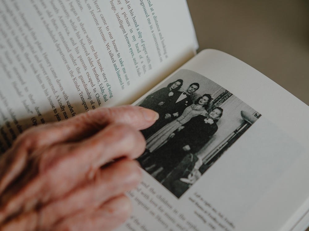 Estelle Laughlin points to a photo of (left to right) herself; her brother-in-law Sol; her sister, Frieda; and her mother, Michla, at Frieda and Sol's wedding in 1948. The book she's holding is her memoir <em>Transcending Darkness: A Girl's Journey Out of the Holocaust.</em>
