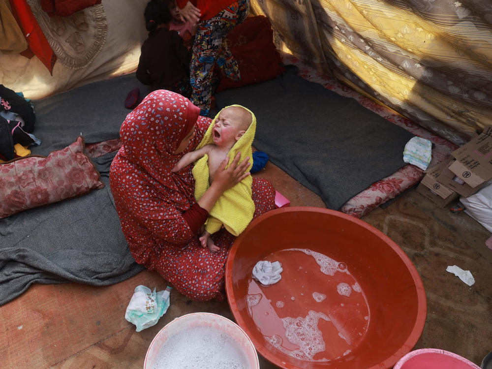 A woman dries a baby in a towel after giving the infant a bath inside a tent at a camp for displaced Palestinians in Rafah, in southern Gaza, on Jan. 18.