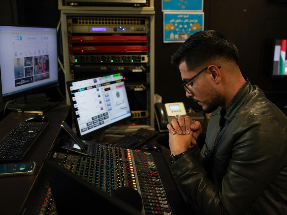 Radio Ajyal producer Mohammed Daher listens to a caller during a weekly radio program in which Palestinians send messages to their relatives in Israeli prisons.