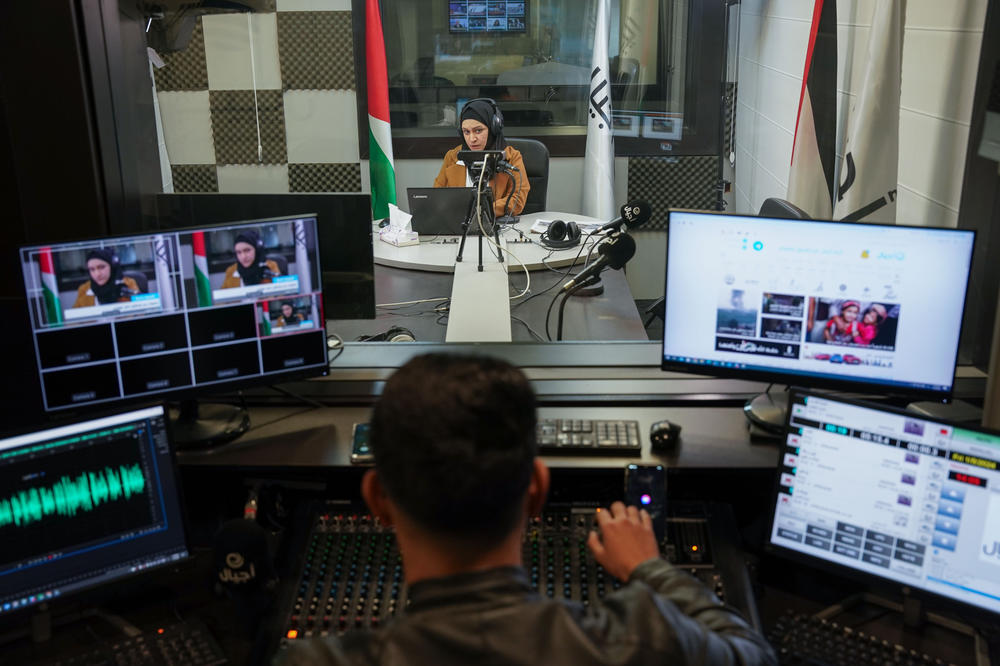 Radio host Ala'a Al-Amleh and audio producer Mohammed Daher listen to a caller during a live radio program which broadcasts messages from Palestinians to their families in Israeli prisons.