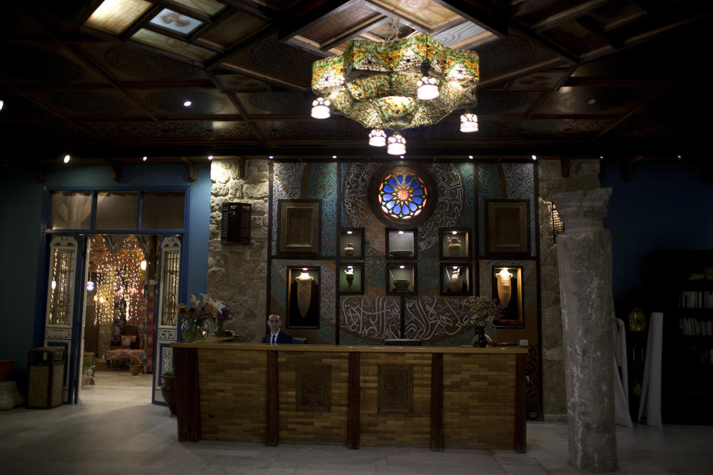 An employee sits behind the reception desk of Al-Mathaf Hotel in Gaza City, in 2019.