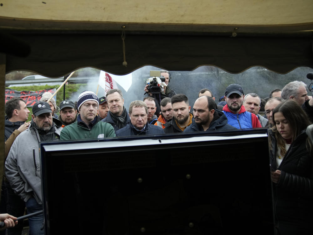 Farmers watch French Prime Minister Gabriel Attal announcing new measures for farmers on a blocked highway on Thursday in Chilly-Mazarin, south of Paris.