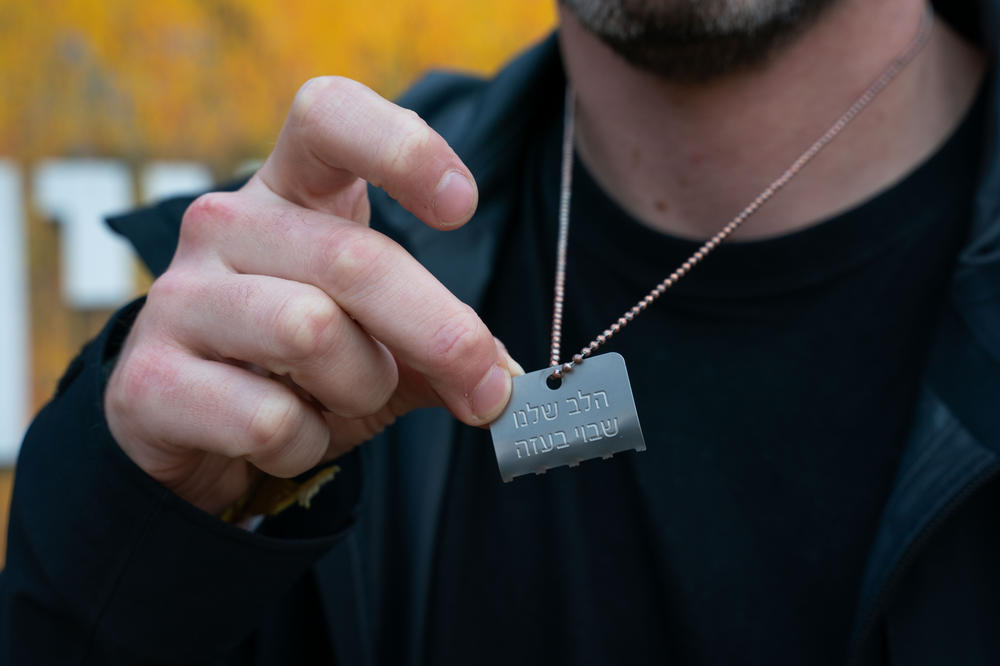 Gil Dickman holds half a dog tag that reads, 