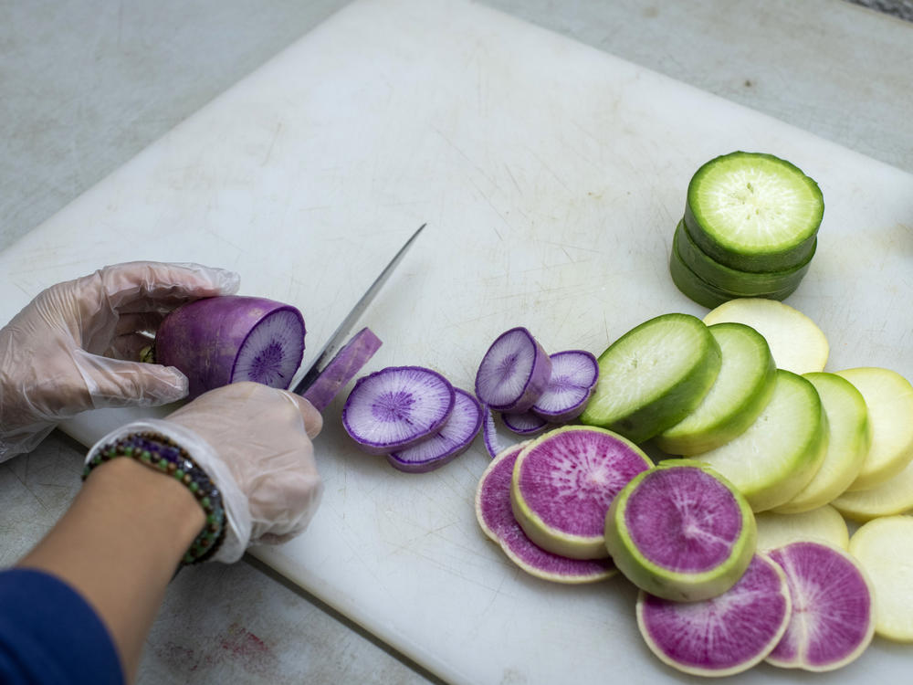 A purple daikon radish grown at Ollin Farms in Longmont, Colo., and other vegetables are prepared to be served at a meeting to discuss support for small Colorado farmers in December.