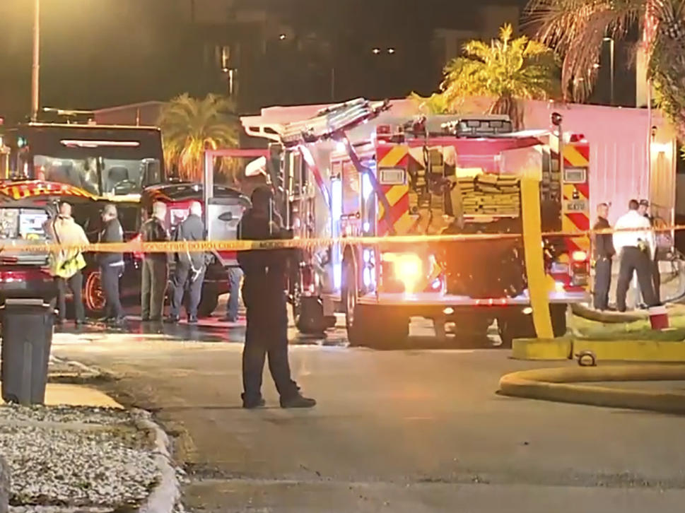 In this image made from video, a fire engine, firefighters and other officials are seen inside police tape on scene of a small plane crash in Clearwater, Florida, Feb. 1, 2024.