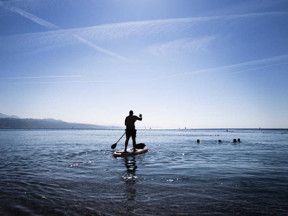 A paddle boarder heads out into the water in Eilat, Israel. Normally, Eilat's beaches and hotels would be busy with tourists.
