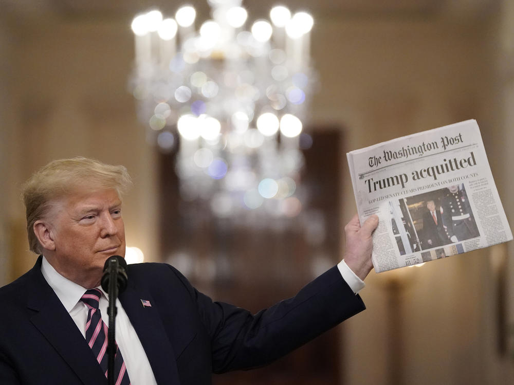 President Donald Trump holds a copy of <em>The Washington Post</em> as he speaks in the East Room of the White House one day after the Senate acquitted on two articles of impeachment in 2020.