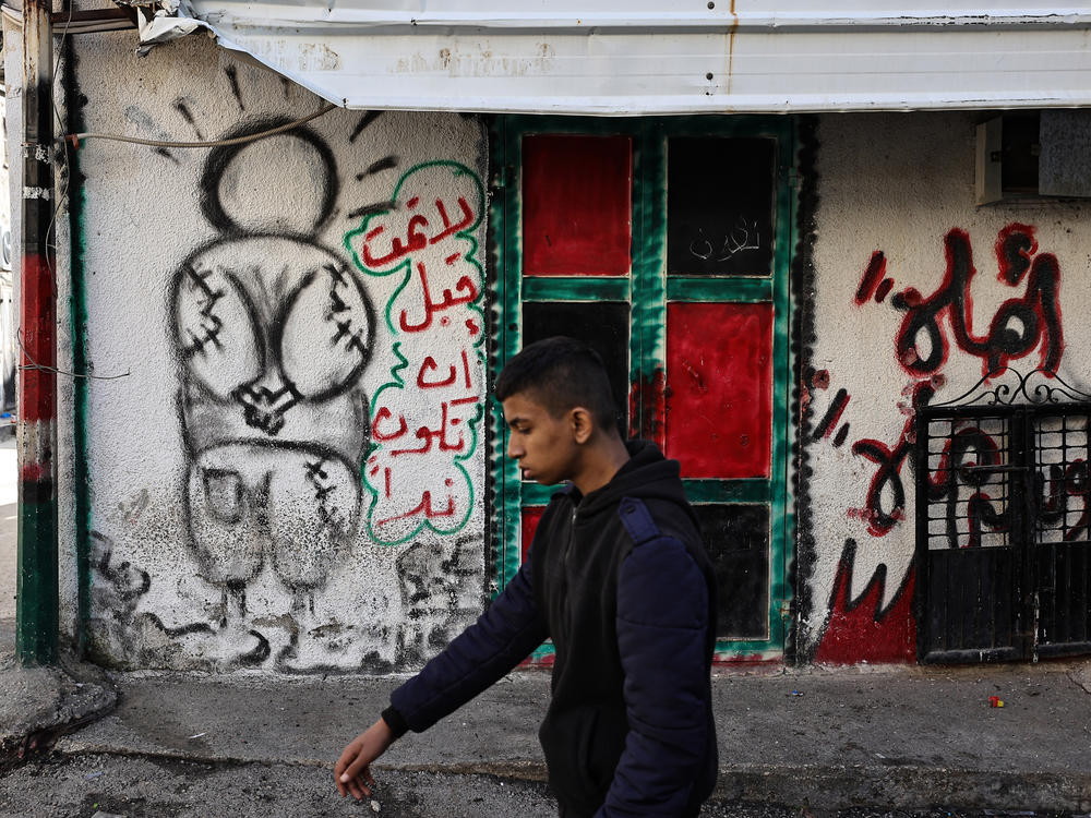 A man walks near a mural of Handala in the village of al-Fara, in the occupied West Bank, following an Israeli raid on Dec. 8.