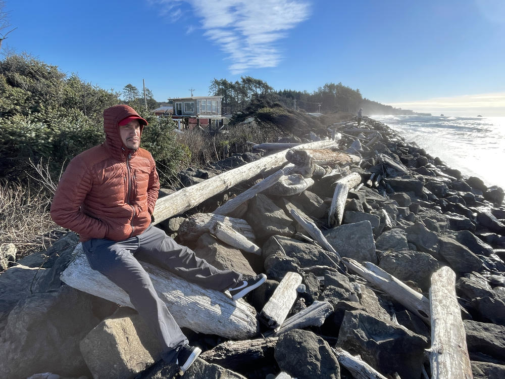 Ryan Hendricks, who is a member of the Quinault Tribal Council, sits on a driftwood log on the Taholah, Wash., sea wall. The coastal tribe is working to move its villages away from the rising waters of the Pacific Ocean and its tsunamis.