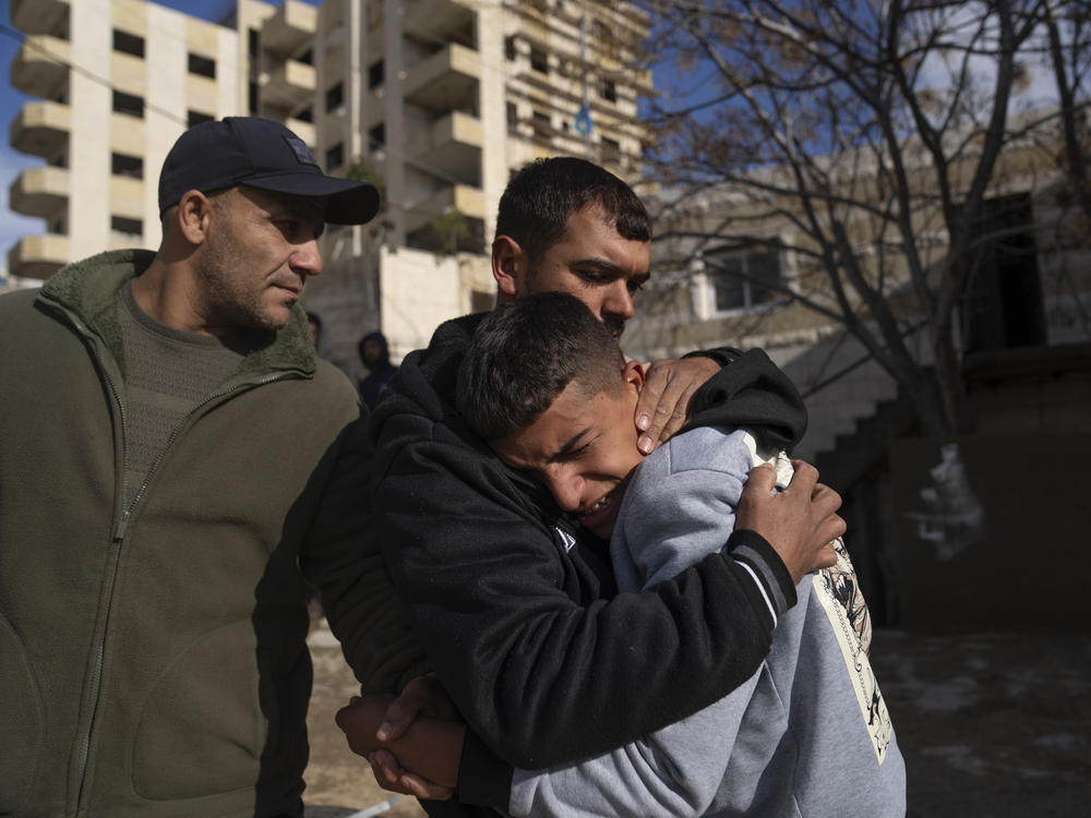 Suleiman Hamed, 14, (right) the brother of Palestinian Abdel Rahman Hamed, 18, cries wile being comforted by a relative during his funeral in the West Bank town of Silwad on Monday, Jan. 29.