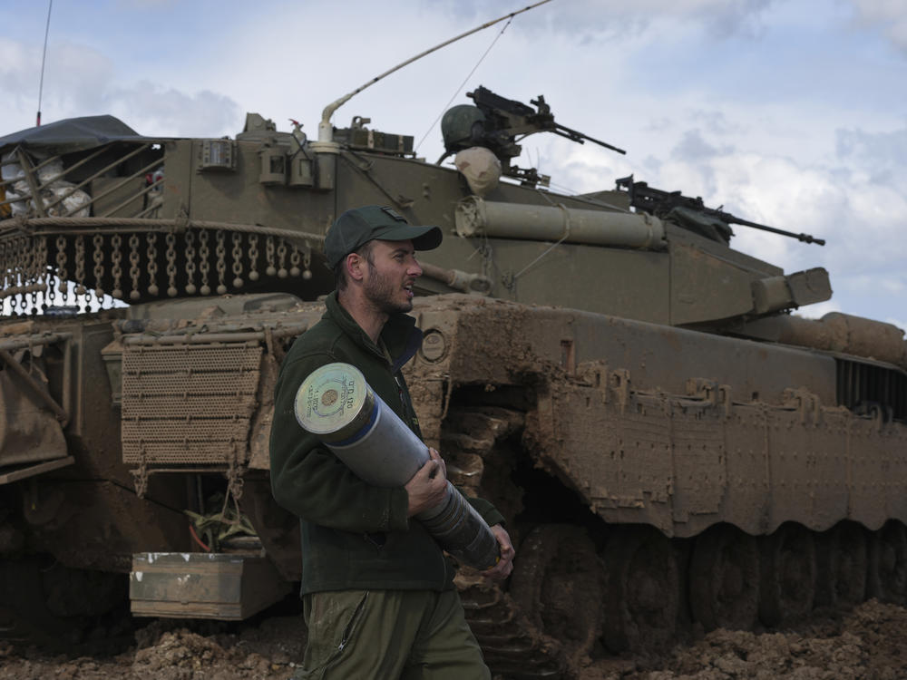 An Israeli soldier carries a tank shell at a staging area in southern Israel, near the border with Gaza, on Thursday, Feb. 1.