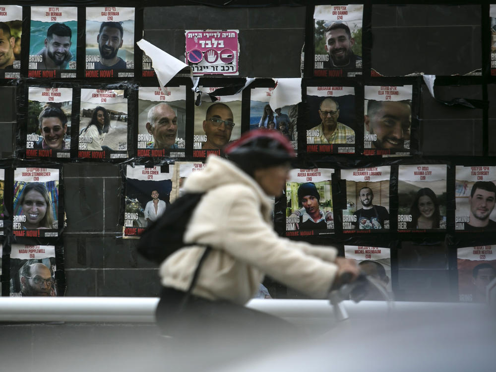 A woman passes a wall covered in photos of hostages held by Hamas on Tuesday, Jan. 30.
