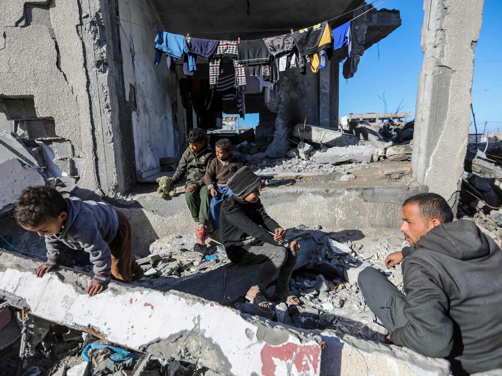 Palestinian Mahmoud Al-Durra, from Gaza City, who was displaced after Israeli raids destroyed his house and his wife was killed, lives on the rubble of someone else's destroyed home while taking care of his four children on Wednesday, Jan. 31.