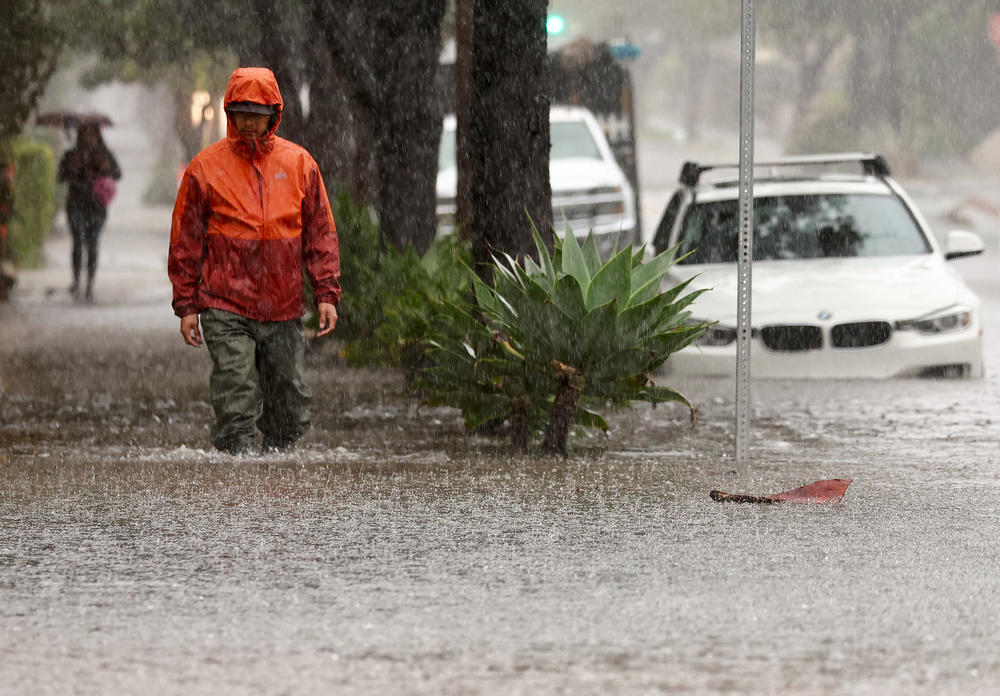 Santa Barbara: A person walks along a flooded street as a powerful long-duration atmospheric river storm, the second in less than a week, impacts California on Sunday.