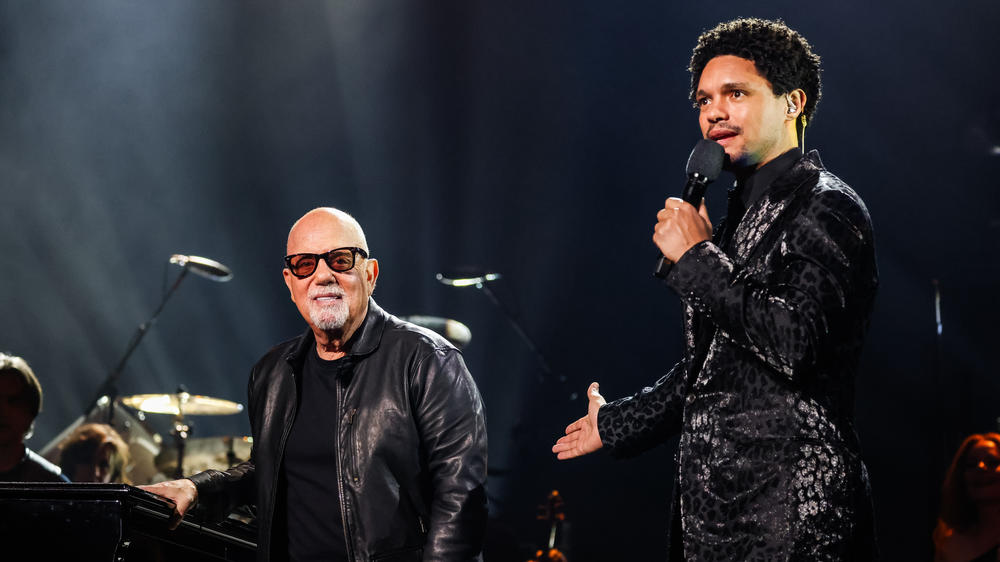 Billy Joel and Trevor Noah speak onstage during the 66th Grammy Awards.