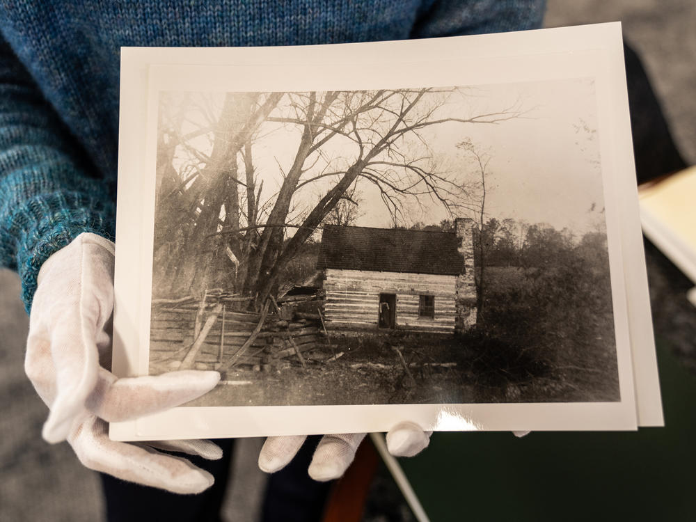 Renata Lisowski, director of the Archive and Research Center at the Chevy Chase Historical Society, holds a photo of a cabin that once sat near the neighborhood of the Rollingwood Burial Ground.