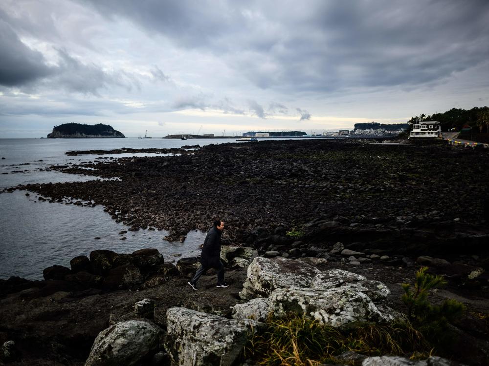 A man takes a morning stroll along the rocky coastline of Seogwipo, the second-largest city on Jeju Island, on Feb. 23, 2023.