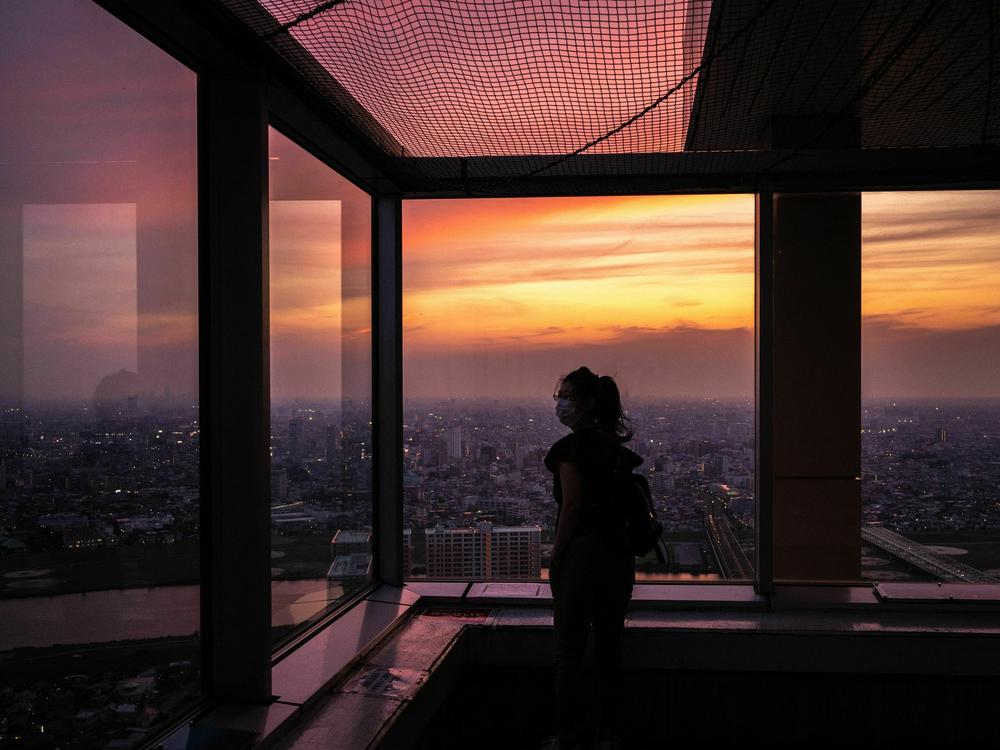 A woman visits the I-Link Town observatory as skylines of Tokyo and Ichikawa are seen during the evening hour in Ichikawa, a city in Japan's Chiba prefecture, east of Tokyo, on June 7, 2023. Japan has a phenomenon known as 