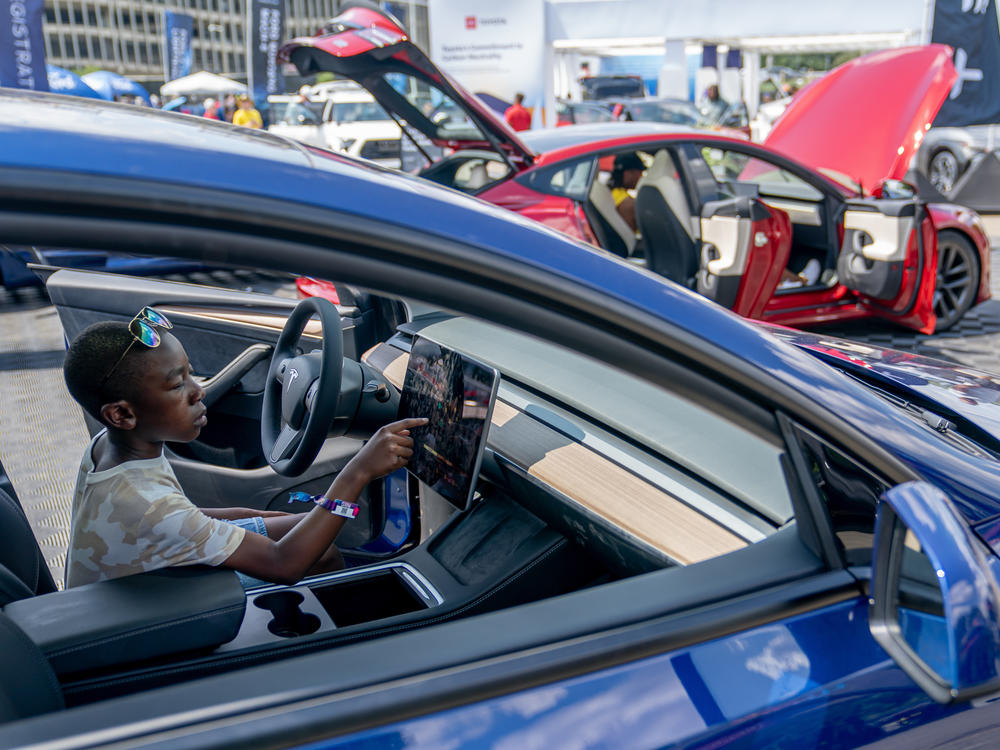 A young attendee examines a Tesla car during the Electrify Expo in Washington D.C. on July 23, 2023. The expo highlighted new and soon-to-be-released electric cars, bikes and other technology. Companies are racing to bring more vehicles to market, in a wider range of segments and at lower prices, to win over skeptical car shoppers. Tesla is working on a lower-cost next-generation platform.