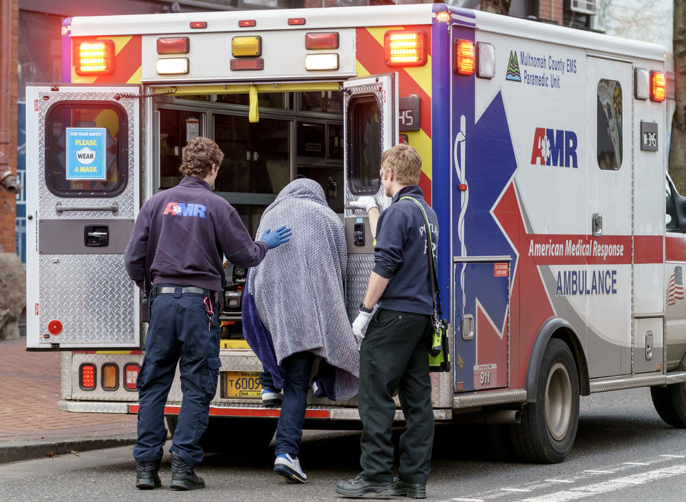 A man who was just revived from a near-fatal overdose climbs into the back of an ambulance.