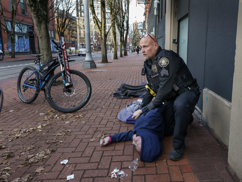 Portland Police Sgt. Jerry Cioeta checks for a pulse after giving a third round of opioid reversal medication to a man found unresponsive in downtown Portland, Ore. The man was revived.