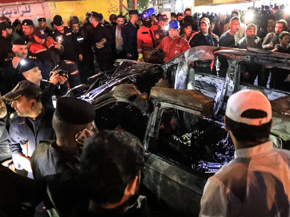 People, rescuers and security forces gather around a vehicle hit by a drone strike, reportedly killing three people, including two leaders of a pro-Iran group, in Baghdad on Wednesday.