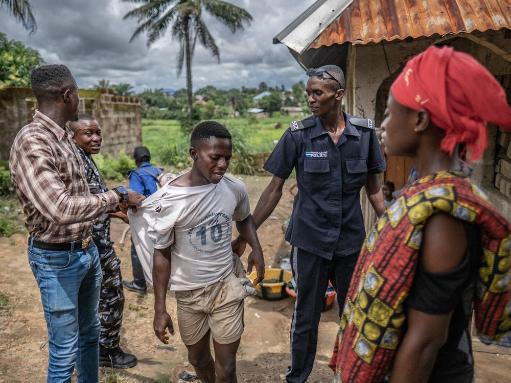 A man is lead away during a police crackdown in Waterloo, Sierra Leone. Police are attempting to enforce a 