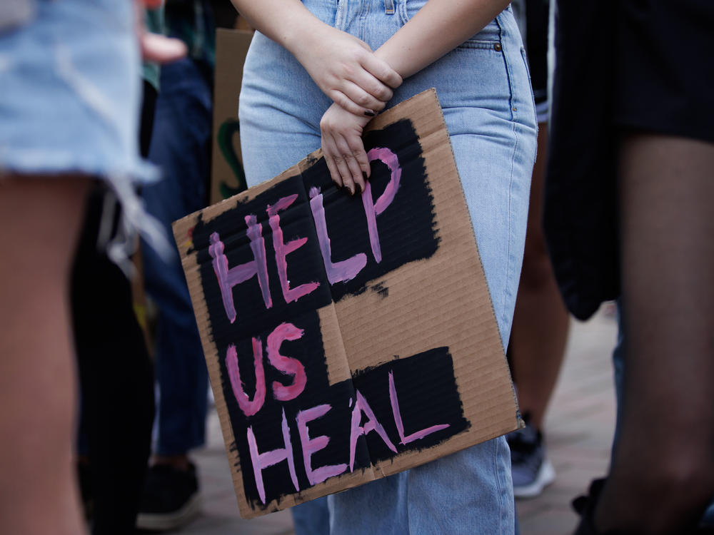 A student at Santa Clara University holds a sign in support of increased mental health services on campus, during a rally in the winter of 2021.