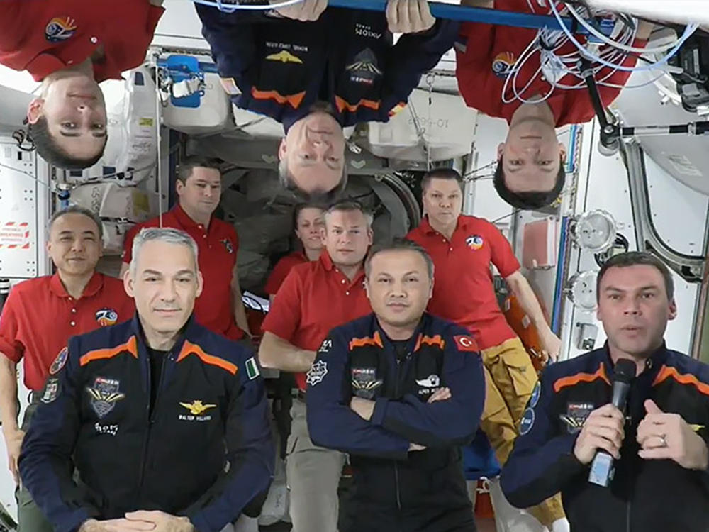 In this image from video provided by NASA, the 11 International Space Station crew members representing Expedition 70 (red shirts) and Axiom Space 3 (dark blue suits) crews gather for a farewell ceremony calling down to mission controllers on Earth on Friday, Feb. 2, 2024.