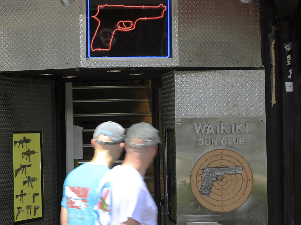 People walk past a gun club on June, 23, 2022, in Honolulu. A ruling by Hawaii's high court saying that a man can be prosecuted for carrying a gun in public without a permit uses pop culture references in an apparent rebuke of a U.S. Supreme Court decision that expanded gun rights nationwide.
