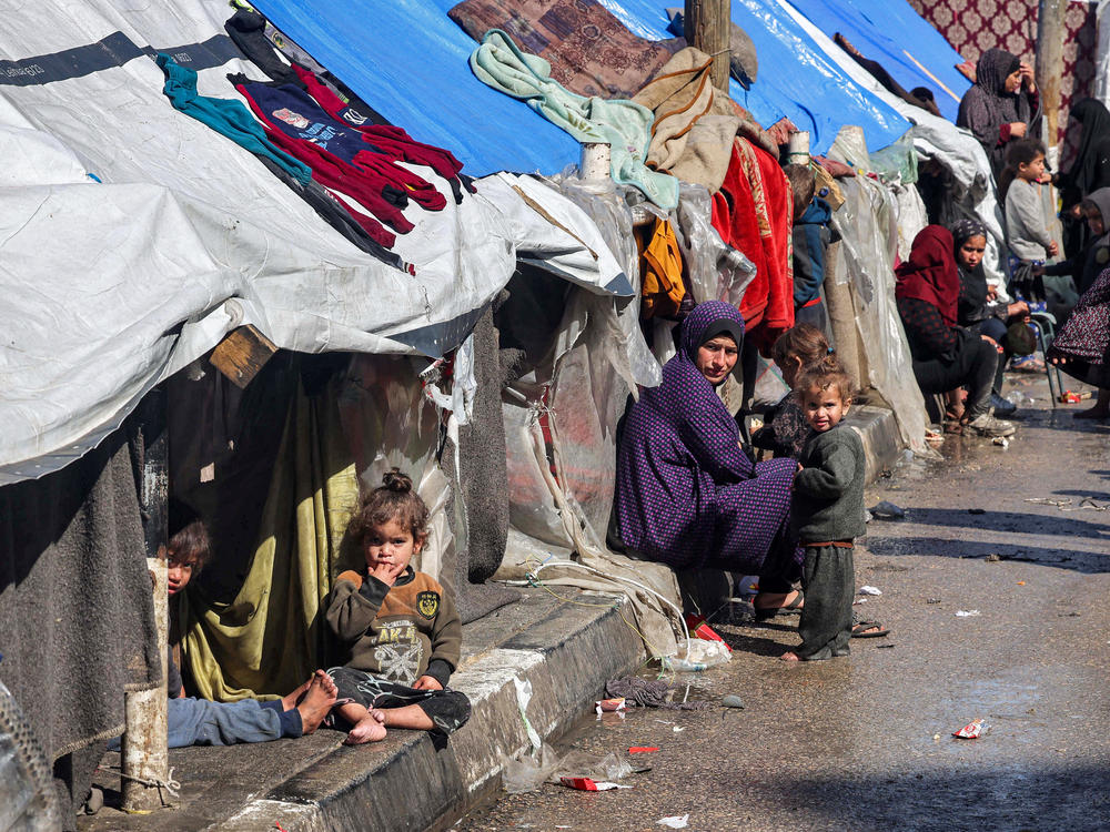 A woman and children sit outside tents sheltering displaced Palestinians in Rafah on Thursday, Feb. 8.
