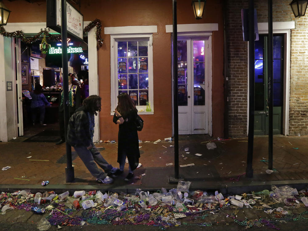 Trash lines the gutter on Bourbon Street, in the early hours of the morning after Mardi Gras, in New Orleans, Feb. 18, 2015. It's a beloved century-old Carnival season tradition in New Orleans — masked riders on lavish floats fling strings of colorful beads or other trinkets to parade watchers clamoring with outstretched arms.