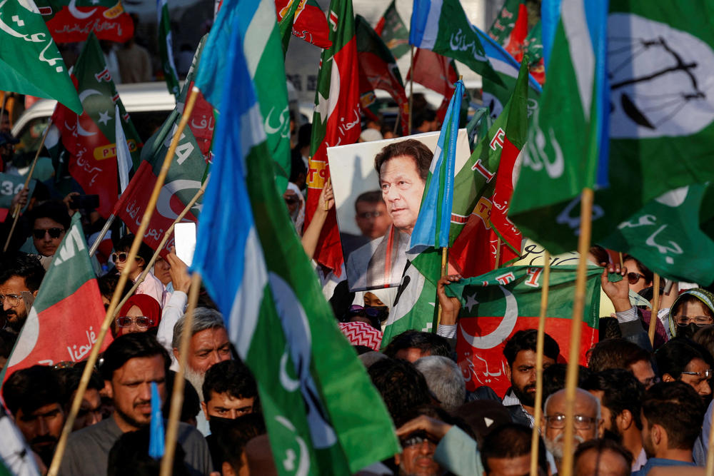 A portrait of the former Prime Minister Imran Khan is seen amid flags of Pakistan Tehreek-e-Insaf (PTI) and the religious and political party Jamat-e-Islami (JI) as supporters attend a joint protest demanding free and fair results of the elections, outside the provincial election commission of Pakistan (ECP)in Karachi, Pakistan February 10, 2024.