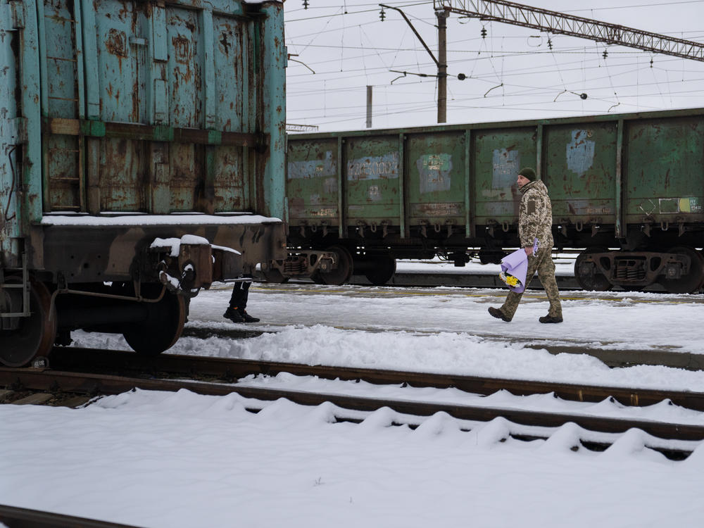 Soldiers hold flowers as they wait for their wives and girlfriends to arrive to the Kramatorsk train station.