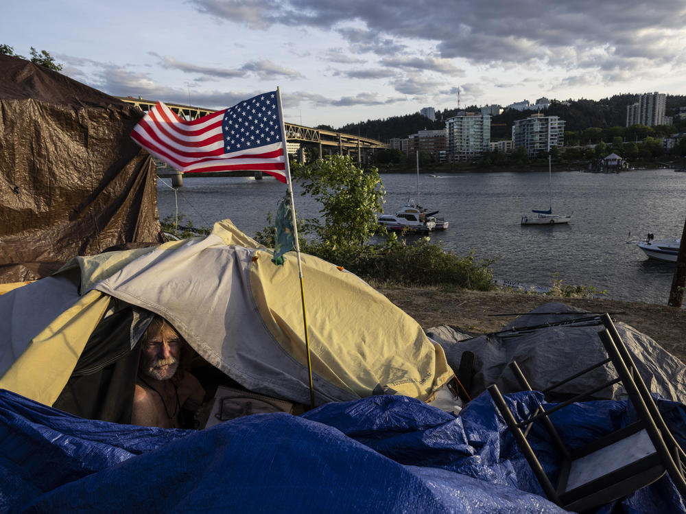 A man named Frank sits in his tent with a river view in Portland, Ore., in 2021. A lawsuit originally filed in 2018 on behalf of homeless people in the Oregon city of Grants Pass is set to go before the U.S. Supreme Court in April.