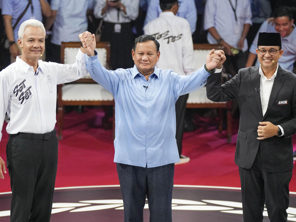 Presidential candidates from left, Ganjar Pranowo, Prabowo Subianto and Anies Baswedan hold hands as they pose for photographers after the first presidential candidates' debate in Jakarta, Indonesia, Dec. 12.