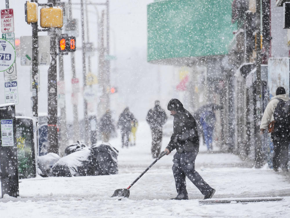 A person clears off a sidewalk during a winter snow storm in Philadelphia on Tuesday.