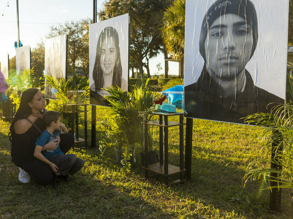 Mariana Rocha holds her son Jackson as she observes a photo of her cousin Joaquin Oliver at a memorial on the fifth anniversary of the Marjory Stoneman Douglas High School mass shooting.
