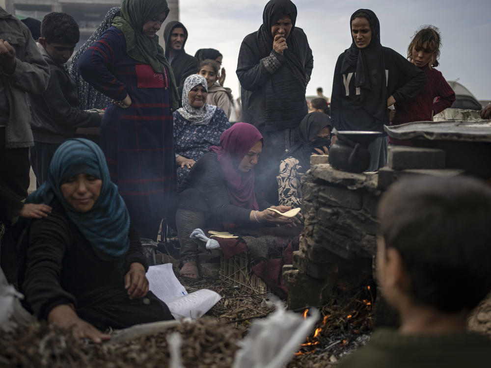 Palestinians displaced by the Israeli bombardment wait for their turn to bake bread at the makeshift tent camp in the Muwasi area in Rafah, Gaza Strip, Saturday, Dec. 23.